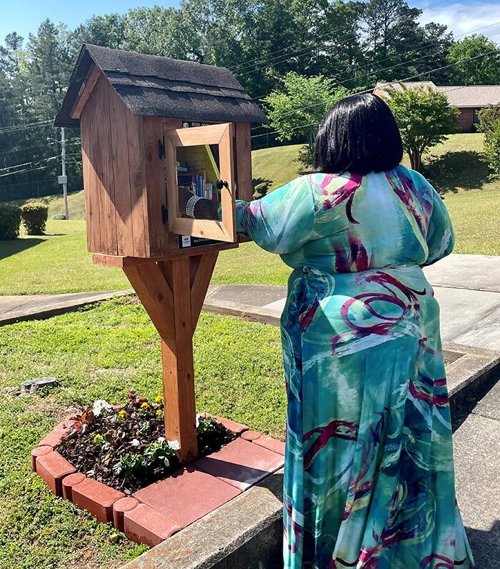 Woman taking a book out of the book nook box outside