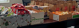 Boxes of food, stacks of pudding cups and rows of brown paper bags sit on the table.