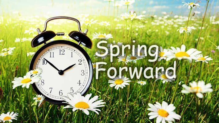 A clock in a field of white flowers with the words Spring Forward.